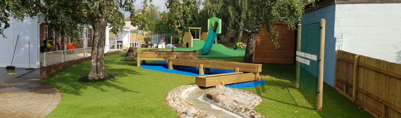 Exterior view of Portfield Academy playground, with slides, artificial grass and bespoke water feature in Chichester, West Sussex