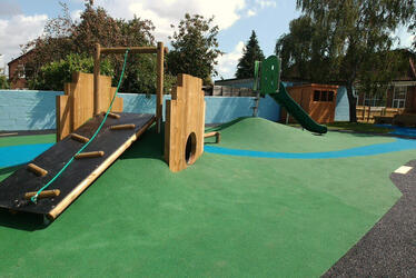 Two landscaped peaks house a climbing frame and slide with a balance beam between the two Two landscaped peaks house a climbing frame and slide with a balance beam between the two